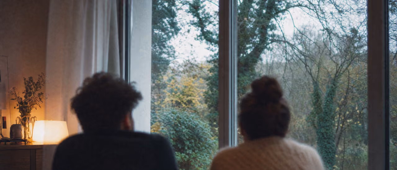 Couple de dos regardant le jardin depuis un intérieur chaleureux