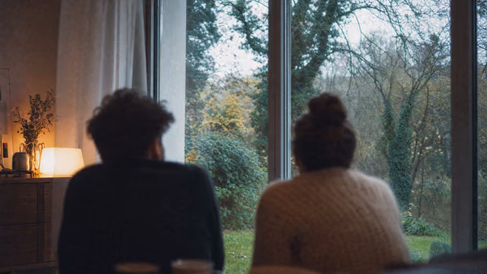 Couple de dos regardant le jardin depuis un intérieur chaleureux